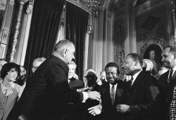Martin Luther King reçu par la président des États-Unis, Lyndon B. Johnson pour célébrer le vote du Voting Rights Act que M. L. King a prôné durant des années. Cette loi interdit aux États d’imposer des limitations au droit de vote, entre autres au motif de la couleur de peau, le 6 août 1965. Photo Y. R Okamoto, Bibliothèque et Musée Lyndon B. Johnson.